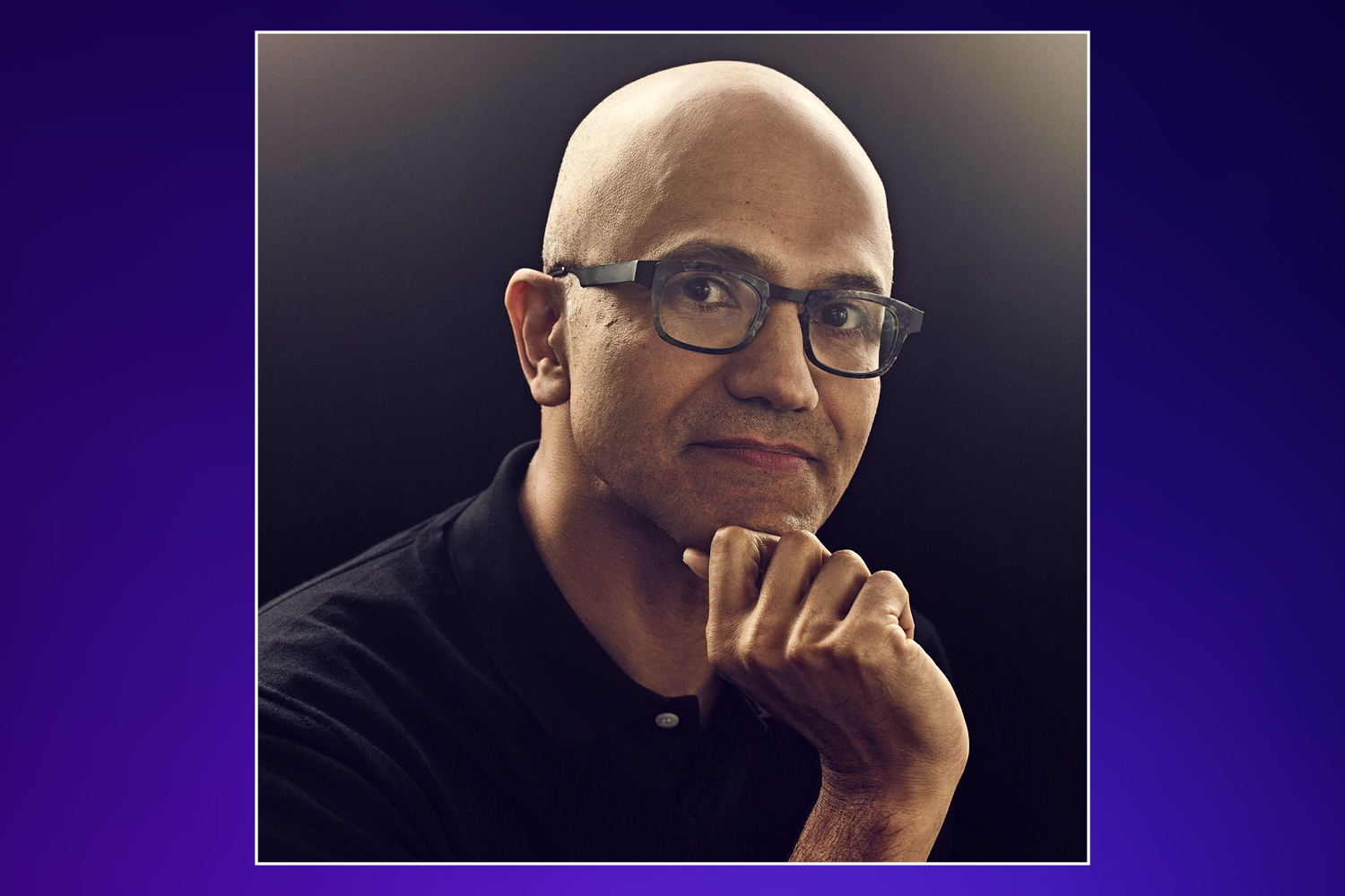 Satya Nadella, CEO of Microsoft, wearing glasses and a black polo shirt, with his hand resting on his chin.