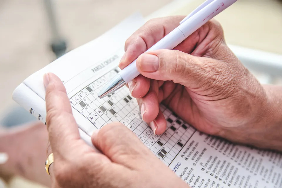 View of an old person completing a crossword puzzle.