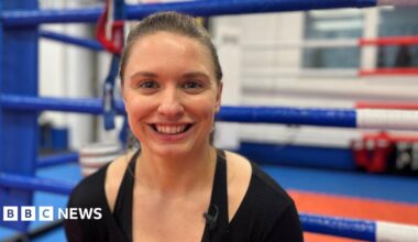 Kat Samuelson pictured at the Rittijak Gym in Swanscombe. Kat is wearing a black top and is smiling to camera. She is sat outside a boxing ring at the gym.