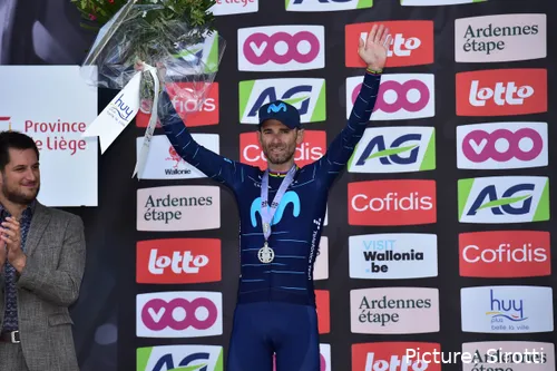 Alejandro Valverde stands on the podium with his arms aloft