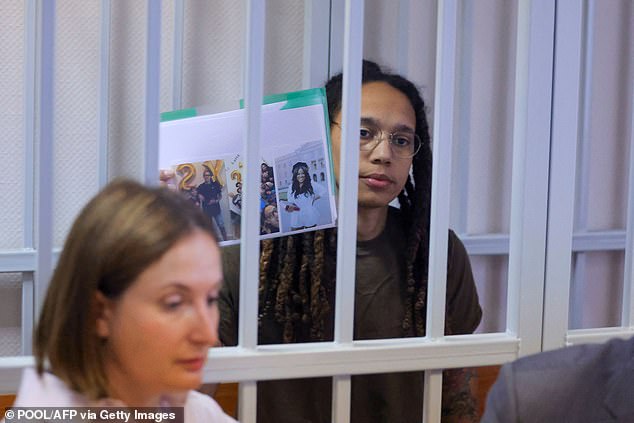 Brittney Griner holds photos inside a defendants' cage before a court hearing during her trial on charges of drug smuggling, in Khimki, outside Moscow on August 2, 2022