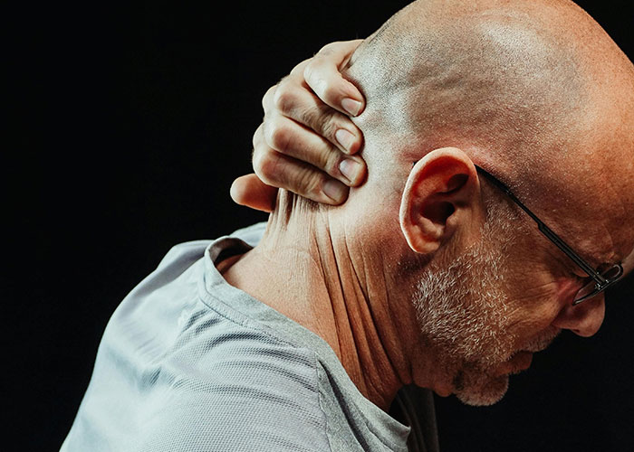 Elderly man holding his neck in pain, illustrating the worst things medical professionals have said to patients.
