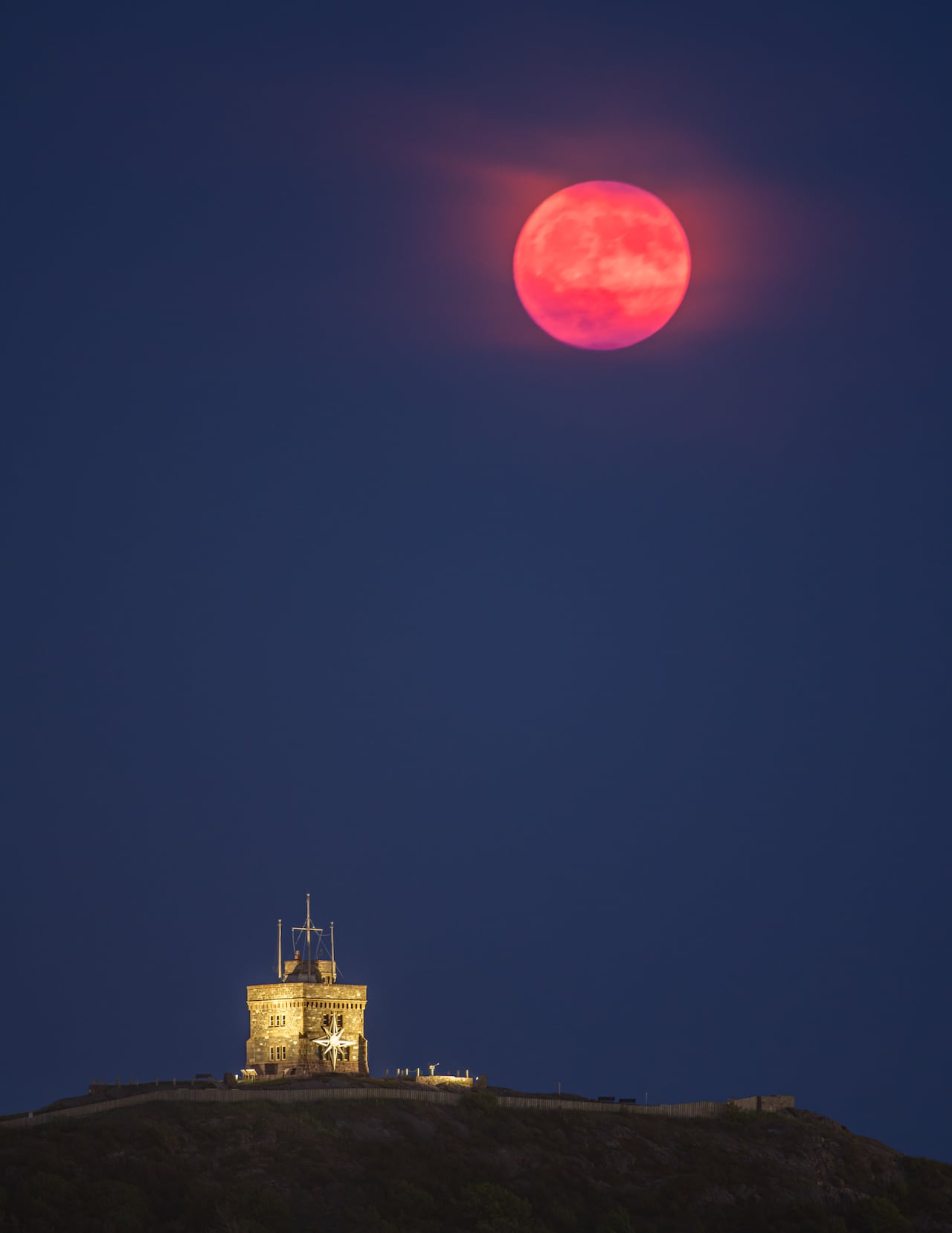 Pink moon at night above signal hill