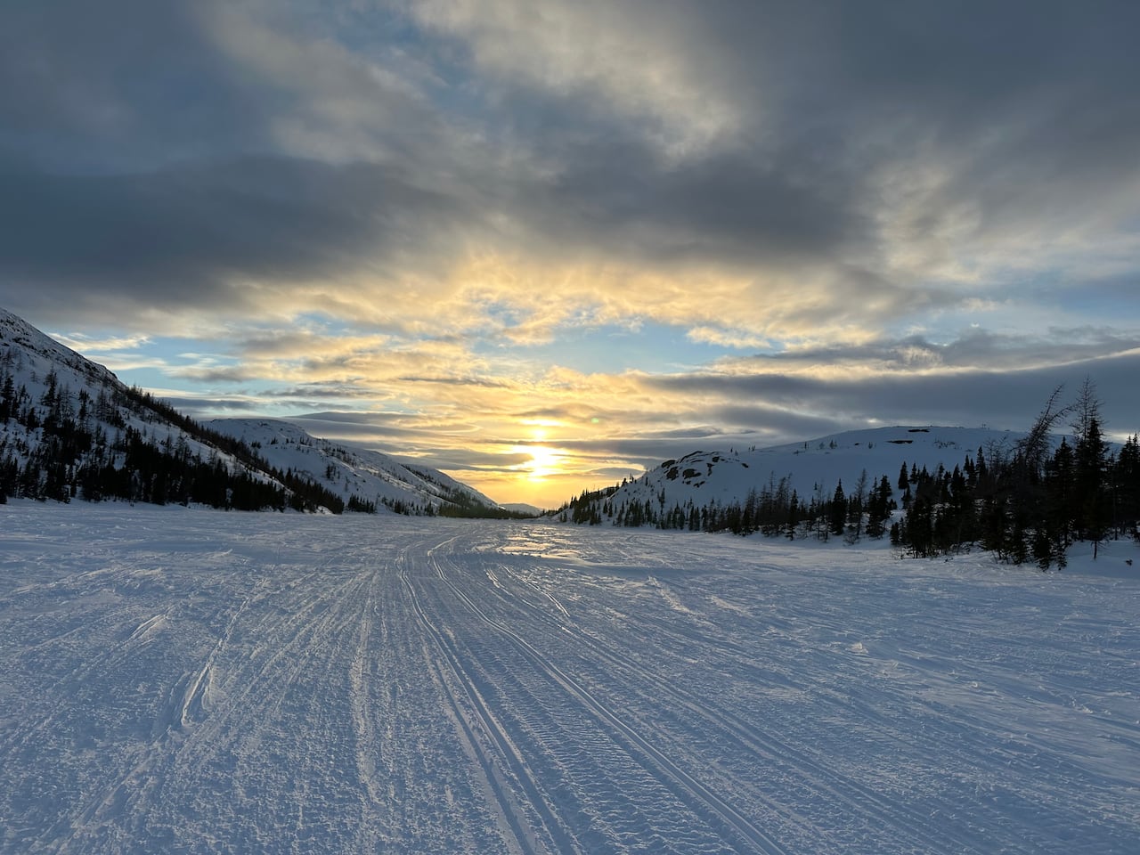 Snowy road and mountains with a sunset. 