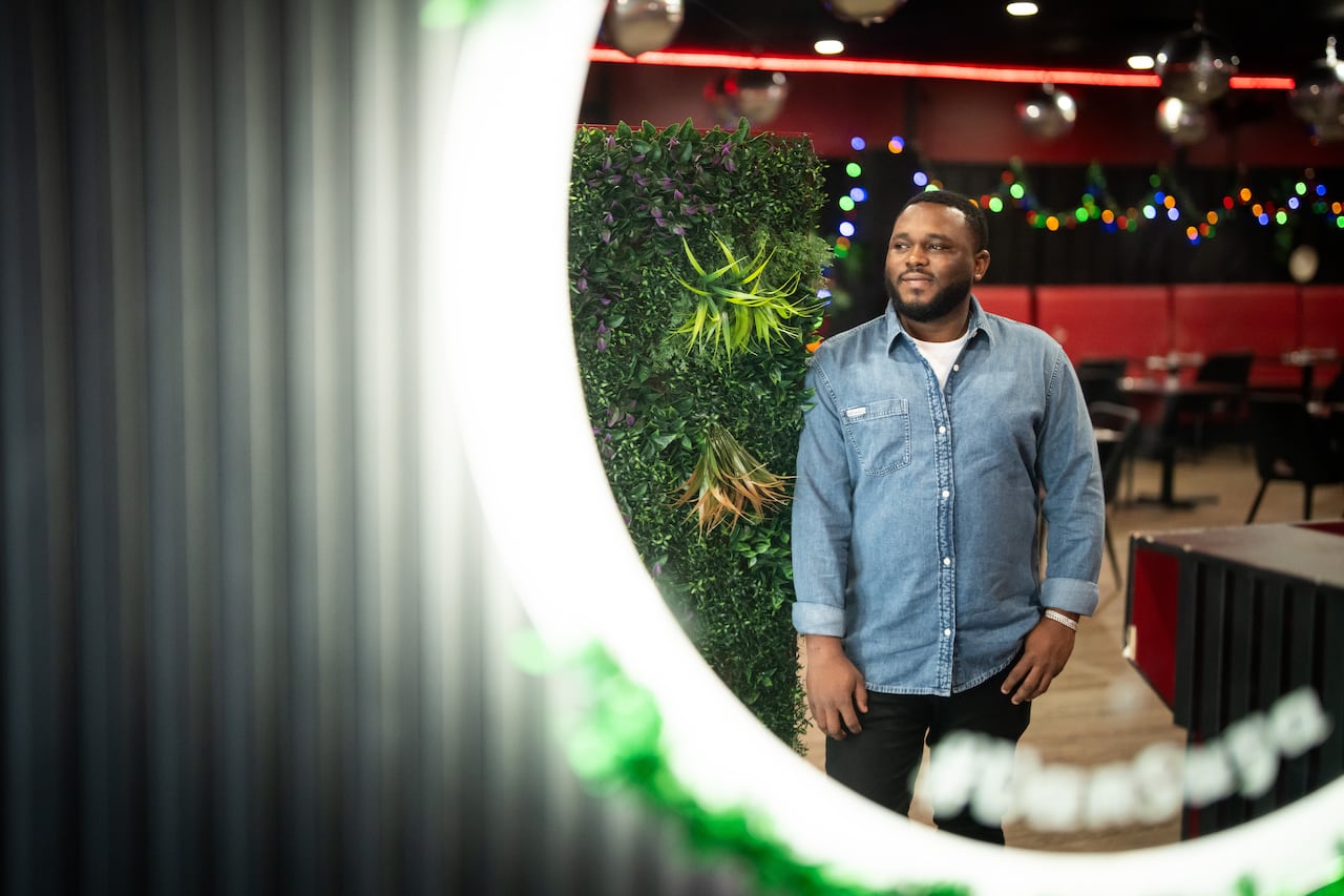 A man wearing a denim shirt stands in a restaurant