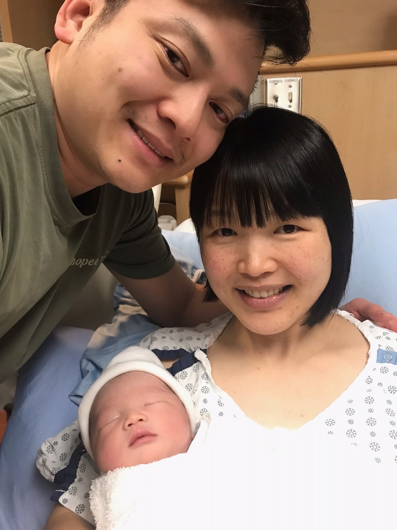 Two people are pictured with a newborn