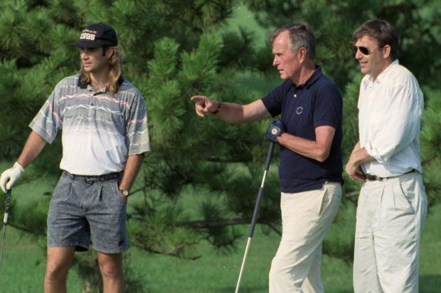 President George H.W. Bush talks with tennis star Andre Agassi, left, and actor Kevin Costner, right, while playing the 18th hole at Andrews Air Force Base