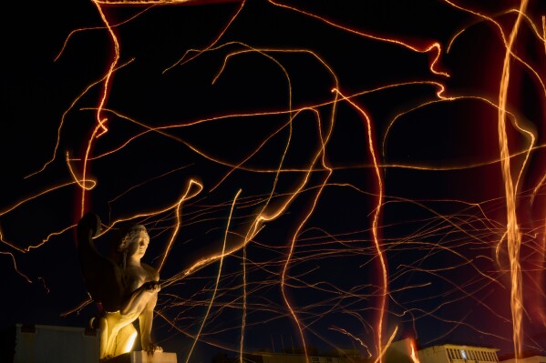 This photo taken with low shutter speed shows tracers cross the sky made by floating lanterns during an event coined The night of wishes, in front of the Athens City Hall, Greece, Dec. 26, 2025. (AP Photo/Petros Giannakouris File)