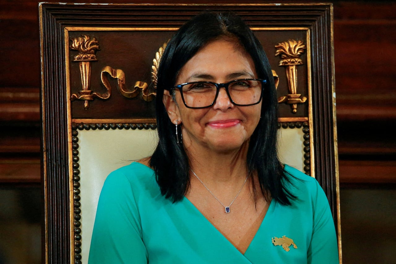 Headshot of a woman with long black hair and glasses, with close mouthed smile