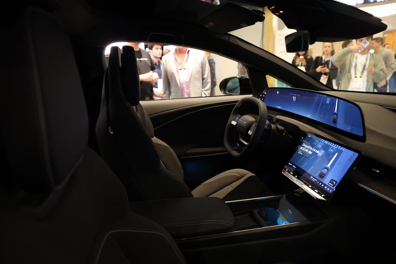 Profile of an vehicle front interior, surrounded by people during a trade show.