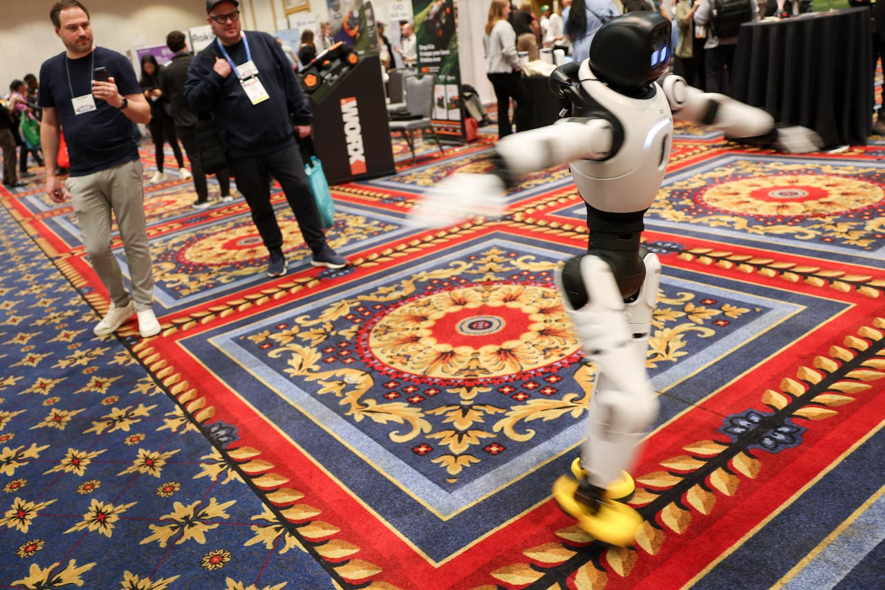 A robot dancing while trade show attendees watch inside a convention centre.