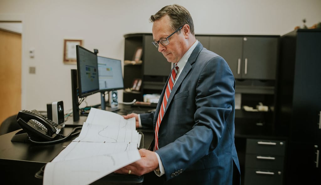 A man wearing a suit shuffling papers in an office.