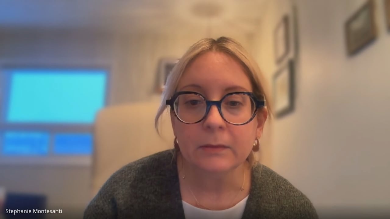 A woman in glasses and blonde hair sits in a room.