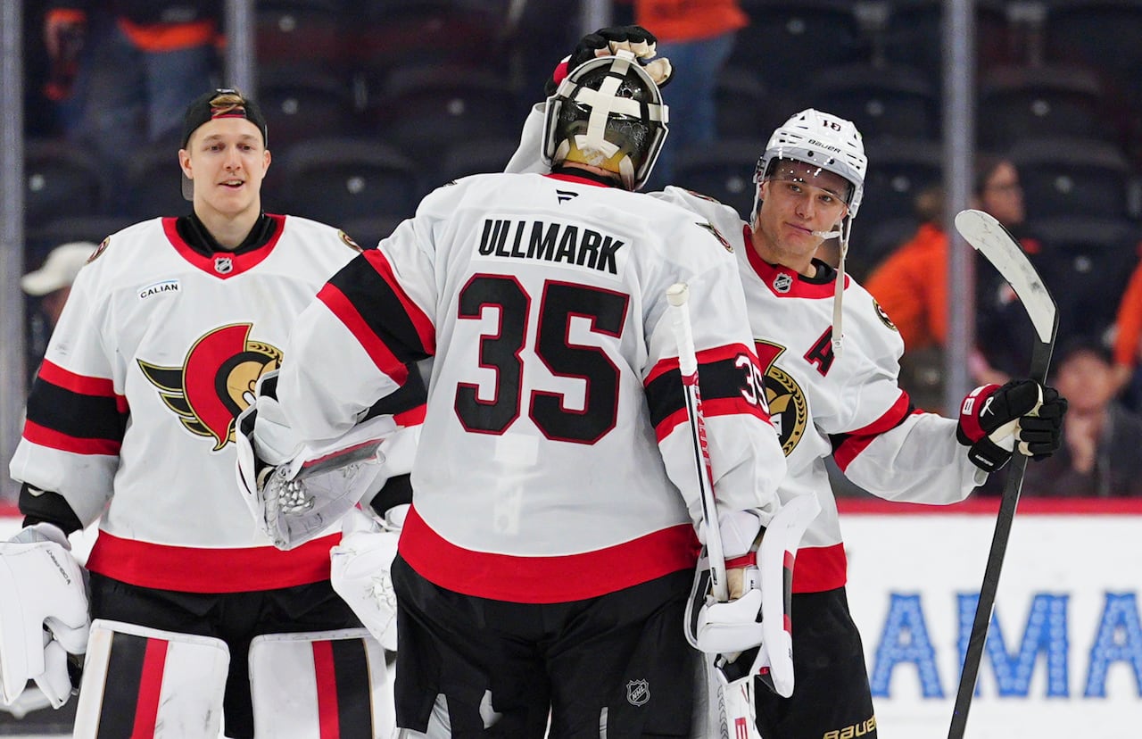 Hockey players wearing white Ottawa Senators jerseys celebrate a win.