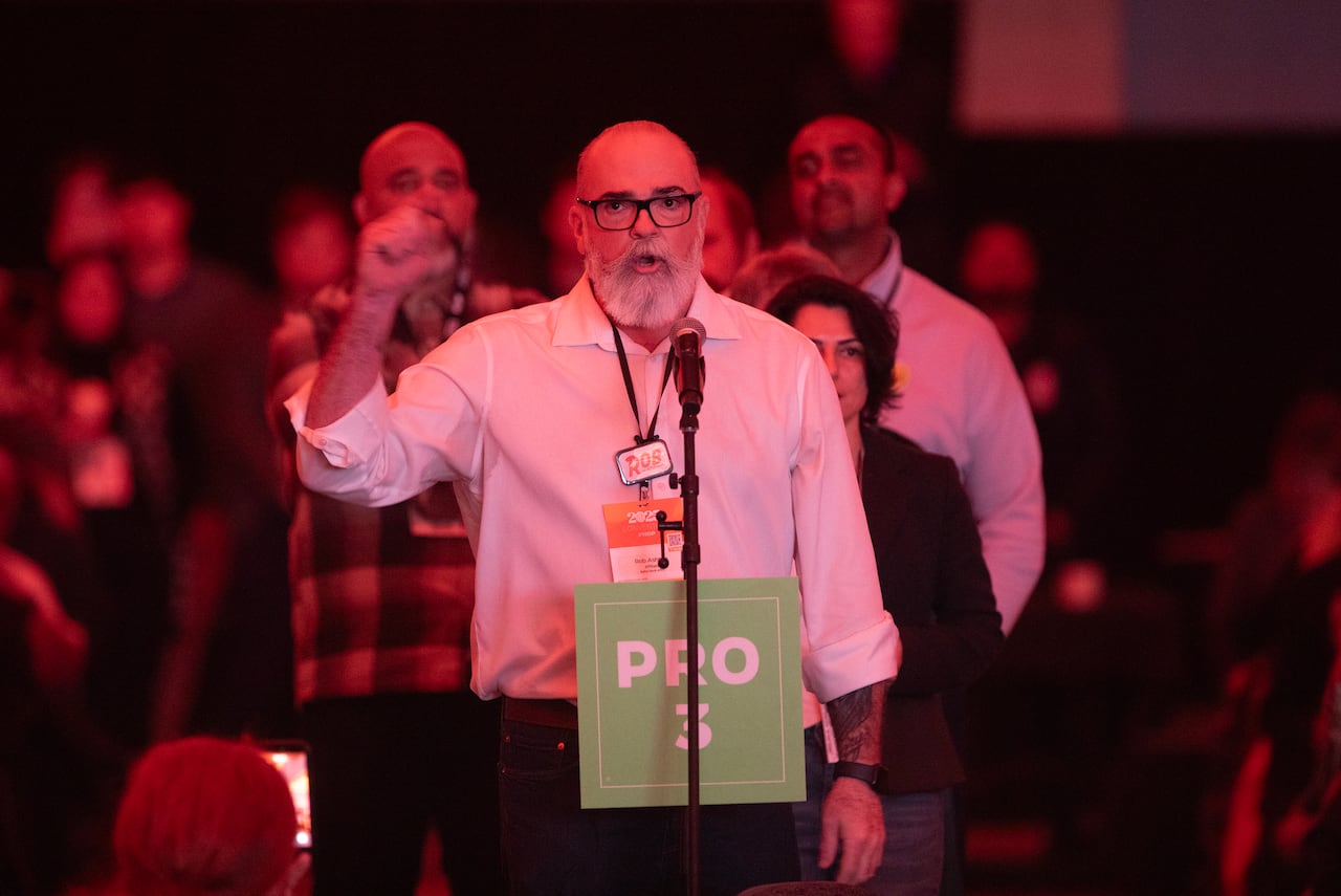 A man speaks at a microphone raising his fists