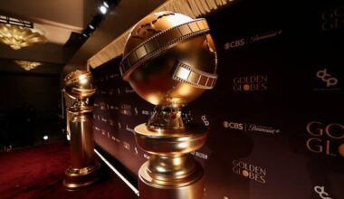Large Golden Globe statues sit on a red carpet.