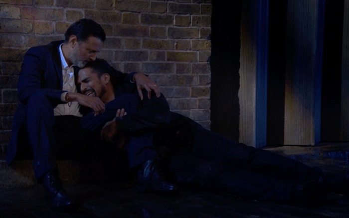 Aaron Thiara as a distraught Ravi Gulati lies crying into the lap of Navin Chowdhry's Nish Panesar on a street in EastEnders.