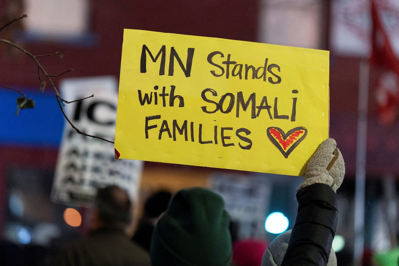 A hand holds a sign that says: MN stands with somali families
