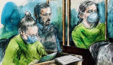 A court sketch showing two women in green prison jumpsuits seated in boxes with a police officer in-between them.