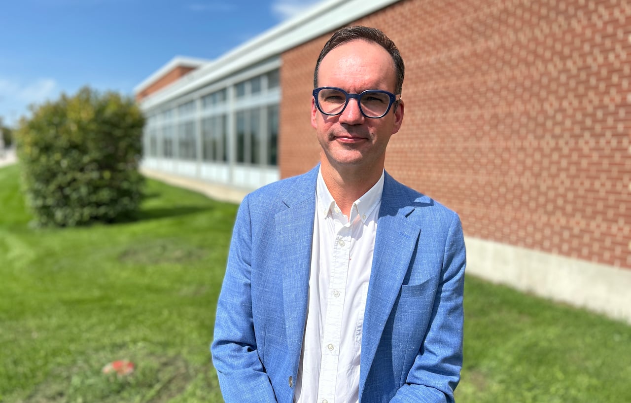 A person is wearing a blue blazer a glasses.