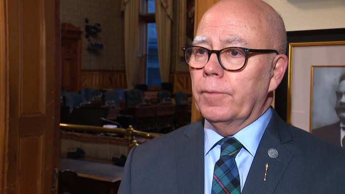 Man, with glasses wearing suit, looking off side camera.