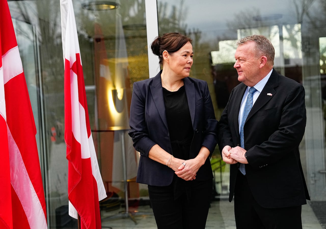 Two people stand near flags.