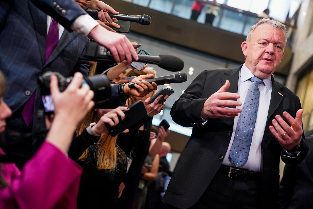 A man gestures while speaking to a scrum of reporters
