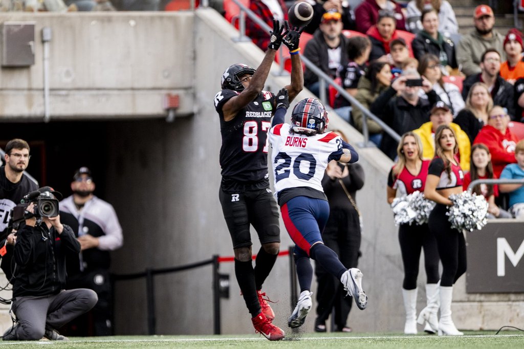 Ottawa Redblacks wide receiver Eugene Lewis (87) scores a touchdown as Montreal Alouettes defensive back Lorenzo Burns (20) attempts a block during first half CFL action in Ottawa, Saturday, Oct. 18, 2025. THE CANADIAN PRESS/Spencer Colby