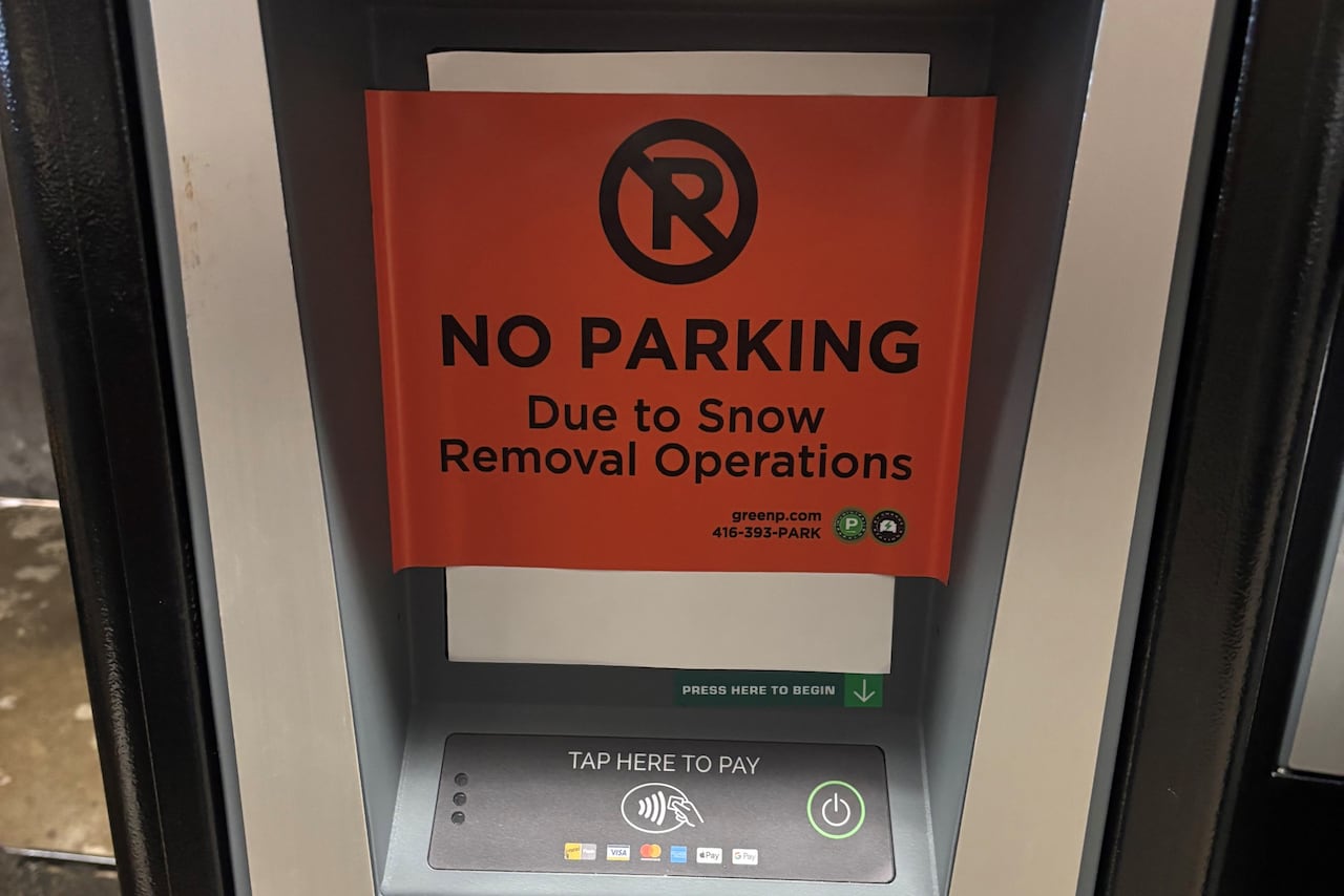 Parking ticket machine with a red sign reading, "No parking due to snow removal operations."