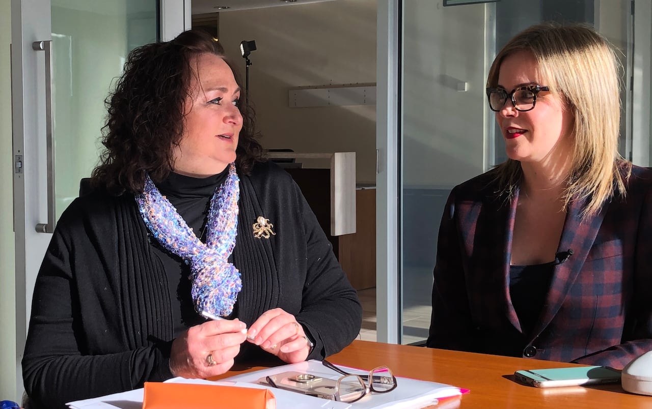A woman and her lawyers speak to each other at a table. 