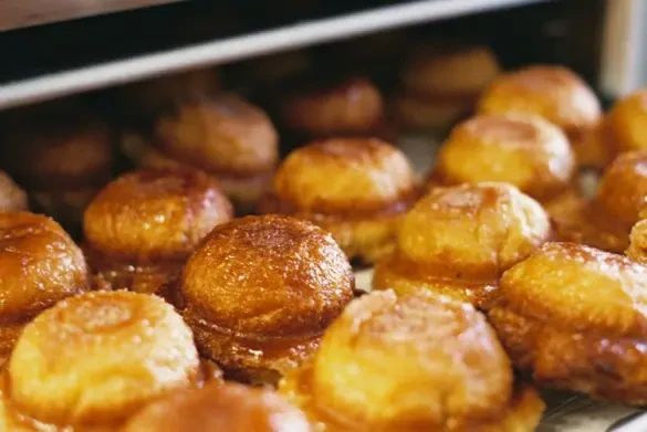 A close up of circular golden brown pasties coming out of an oven.