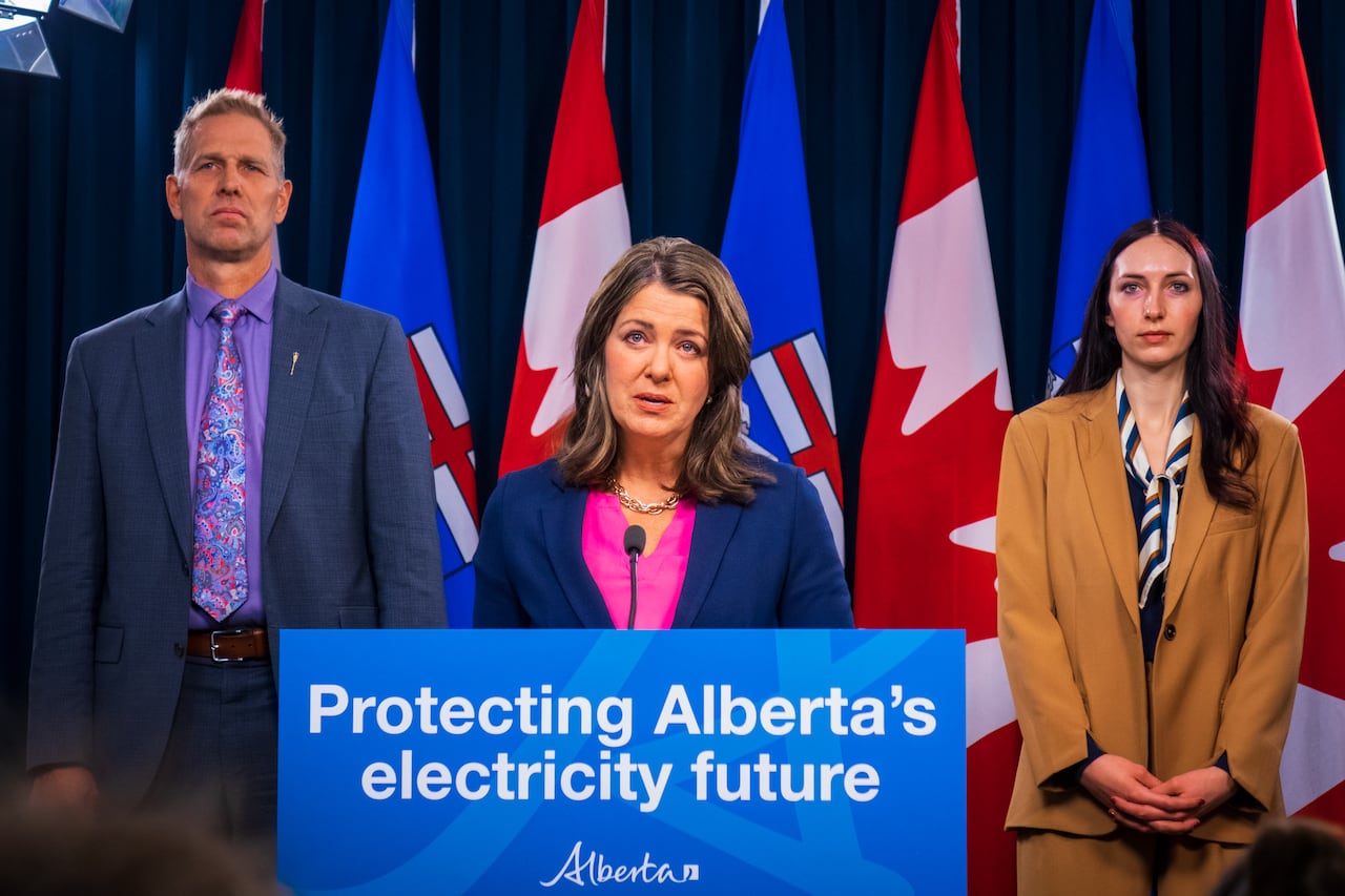 Alberta Premier Danielle Smith speaks at a podium that reads "Protecting Alberta's electricity future" with a man and woman on either side.