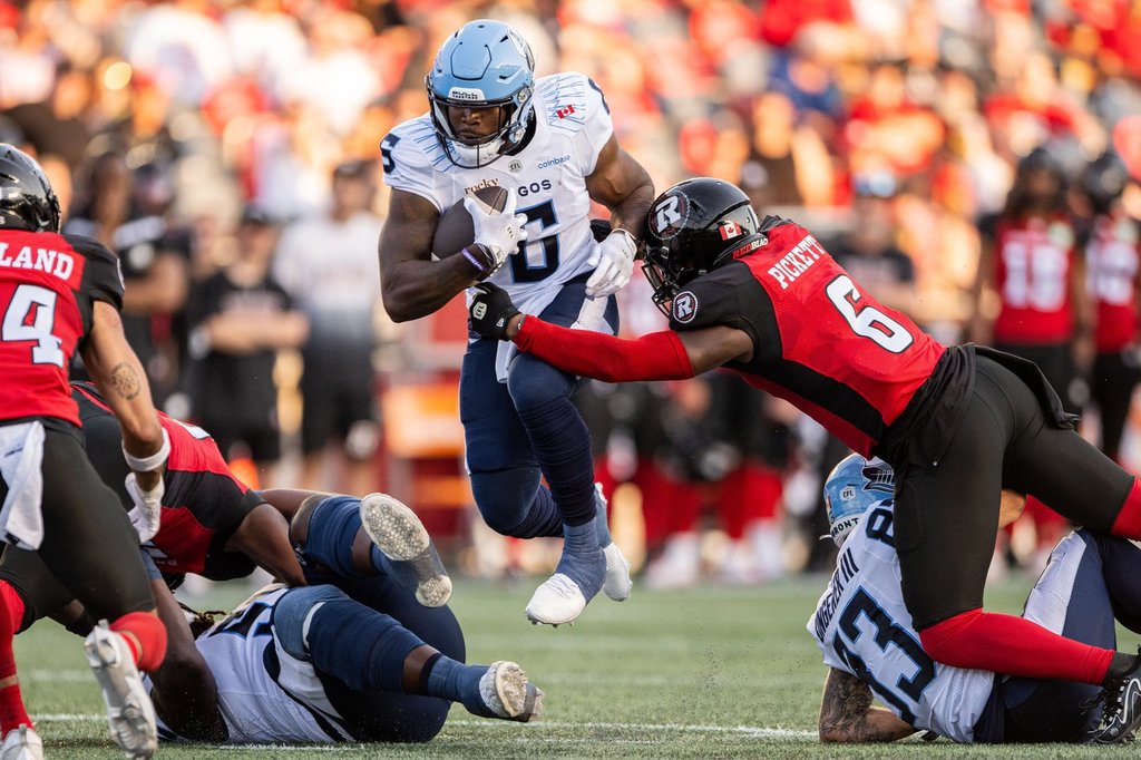 Toronto Argonauts running back Kevin Brown (6) jumps in the air as Ottawa Redblacks linebacker Adarius Pickett (6) makes a tackle during first half CFL football action in Ottawa, on Sunday, June 29, 2025. THE CANADIAN PRESS/Spencer Colby