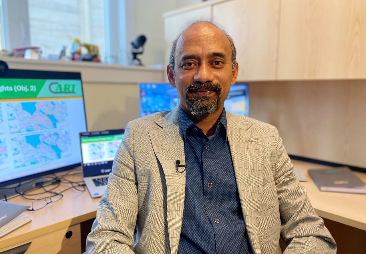 A man in a suit sits in front of computer screens