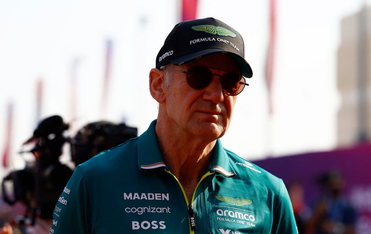 An older man in an Aston Martin baseball cap and shirt. He's wearing sunglasses.