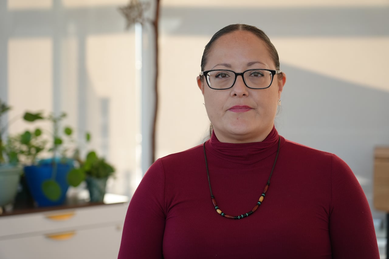 Patricia McCartney wears a red turtleneck sweater, glasses and a beaded necklace