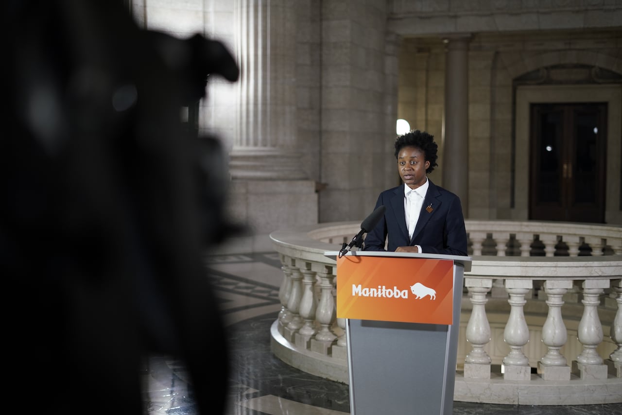 A politician speaks into a microphone on a lectern in government building.