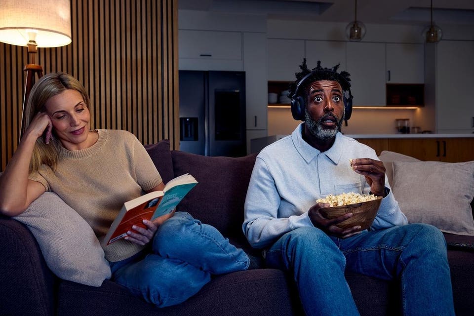 Sennheiser RS275 worn by man eating popcorn while woman sits next to him reading a book