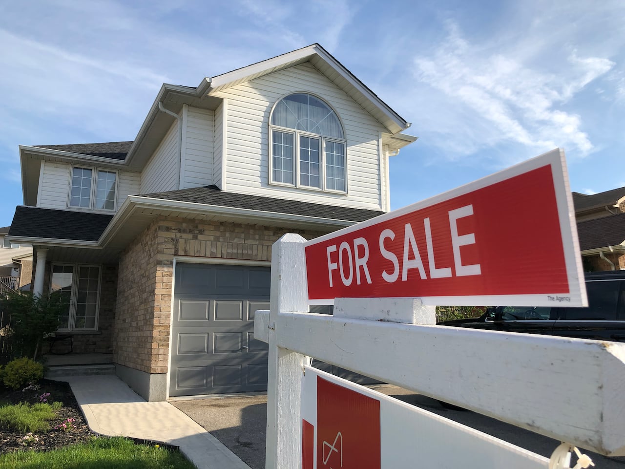 A house with a 'for sale' sign outside it.