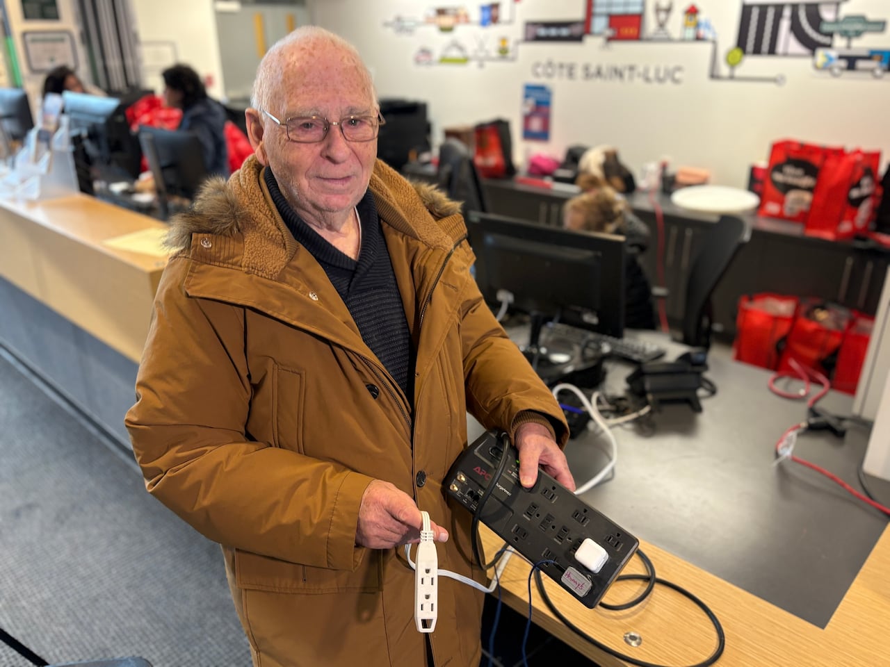 A man wearing a winter jacket holds up an extension cord and power bar.