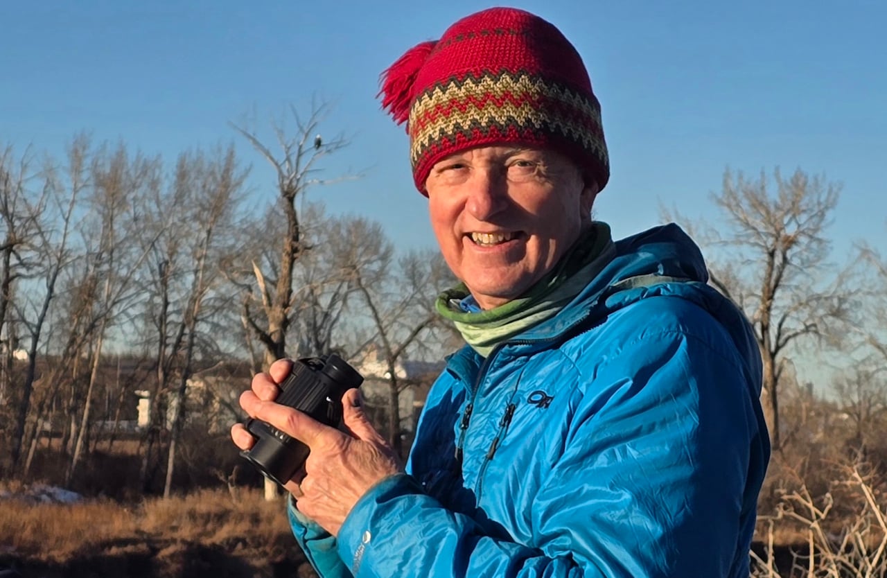 A man holding binoculars in a park.