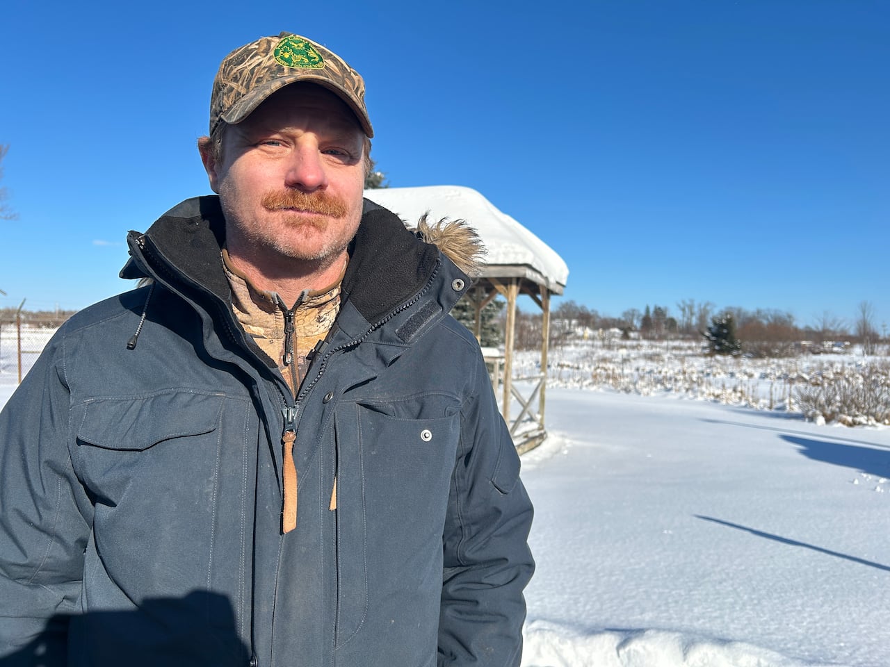 A man in winter clothing poses for a photo in a snowy, outdoor environment.