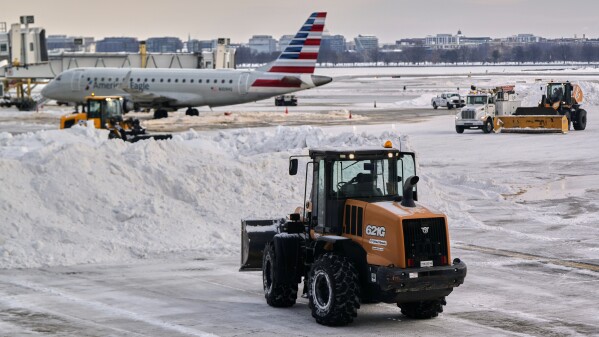 Snow and ice is cleared at Ronald Reagan Washington National Airport, Monday morning, Jan. 26, 2026, in Arlington, Va. (AP Photo/Julia Demaree Nikhinson)