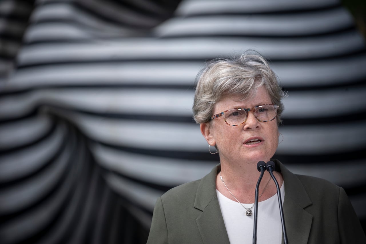 A woman stands in front of a microphone.