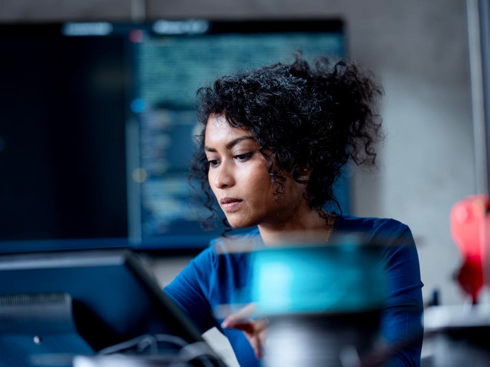 Improve Automate Workflows and Streamline Software Testing with Machine Learning in Software Development. An Asian female software developer coding or debugging code on a computer at her desk in the tech office.
