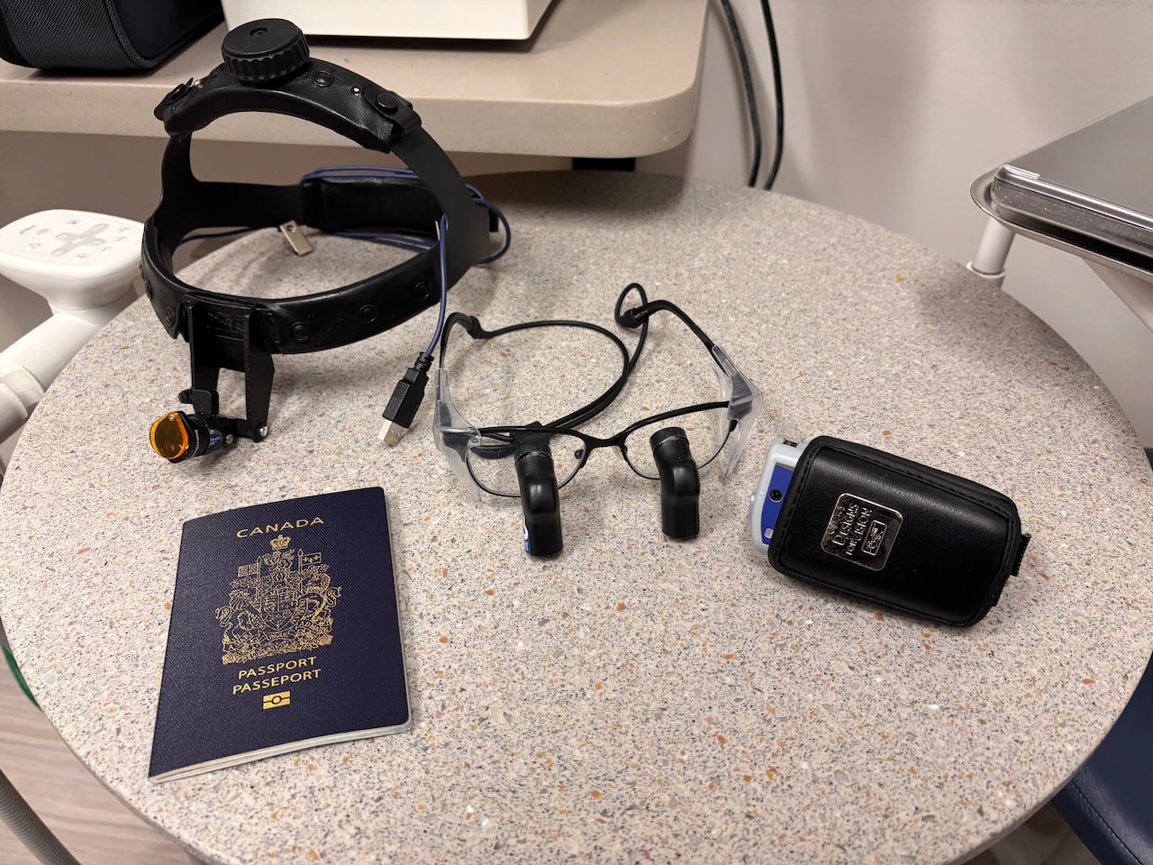 A Canadian passport, a battery and some medical equipment sit on a table.
