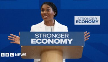 Conservative Party leader Kemi Badenoch gives a speech from behind a podium reading "stronger economy" in front of a blue backdrop.