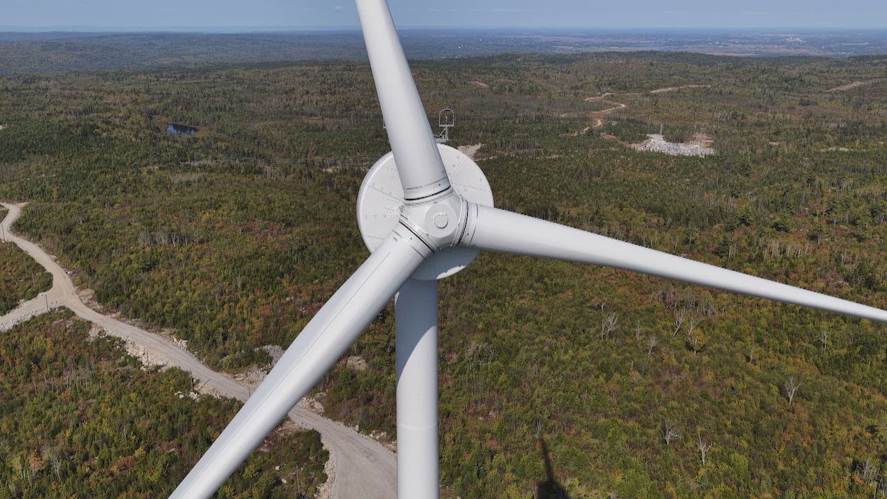 A wind turbine with greenery in the background.