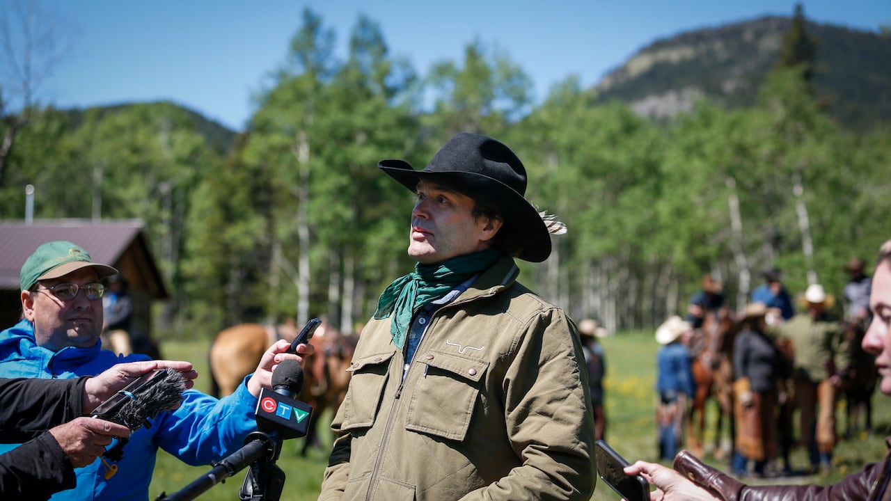 A man in a cowboy hat is seen speaking to reporters.