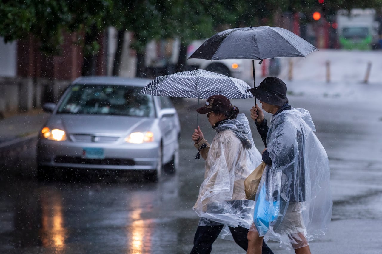 People wearing rain ponchos carry umbrellas